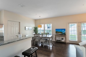 A modern kitchen with a granite countertop, a dining area with a table and chairs, a bench, and a TV in the corner. - Lucaya Village Resort - 4 Bed 3 Bath Townhouse (Kissimmee)