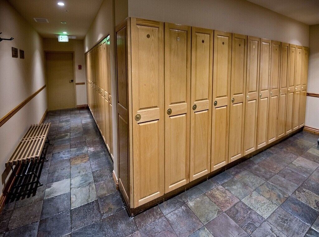 A hallway with a row of wooden lockers, a radiator, and a tiled floor.