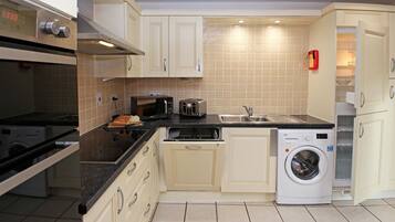 A compact kitchen with a built-in oven, a microwave, a toaster, a sink, and a washing machine.