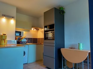 A compact kitchen with a washing machine, a microwave, and a built-in oven.