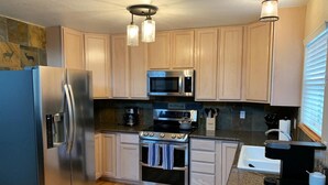 A compact kitchen with a refrigerator, microwave, stove, and sink. - Cozy Cabin with Modern Amenities (Pet Friendly) (Pagosa Springs)