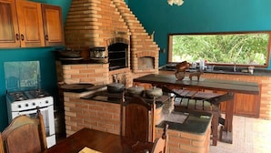 Une cuisine rustique avec un four en briques, des armoires en bois et un coin repas comprenant une table et des chaises.