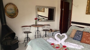 Une chambre d’hôtel confortable avec un lit, une petite table avec des chaises, une cheminée et un miroir au mur.