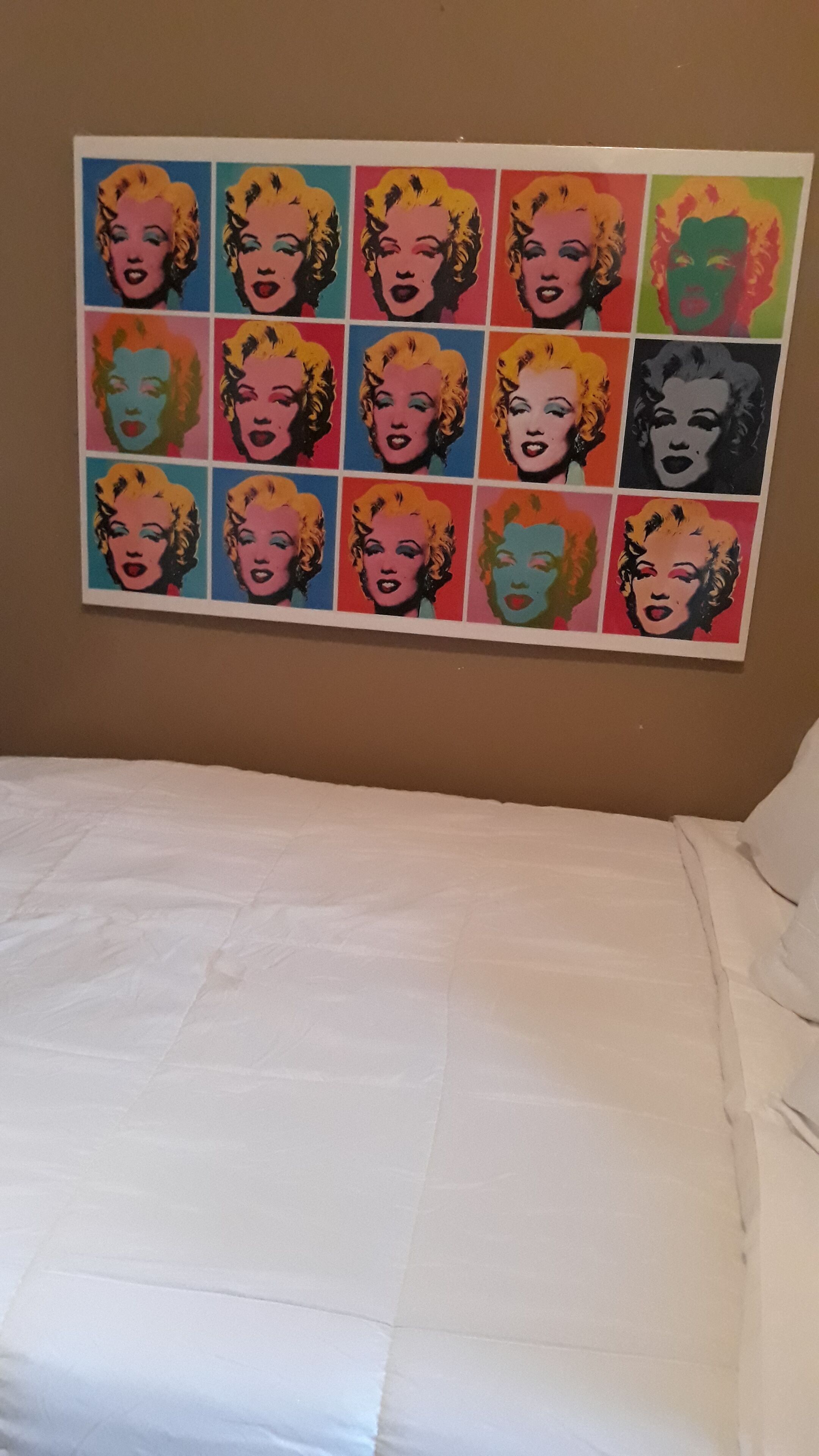 Un dormitorio con cama y un llamativo mural de arte pop en la pared.