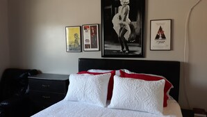 A hotel room with a bed, a dresser, and three framed pictures on the wall. - Historic City view   Suites (Los Angeles)