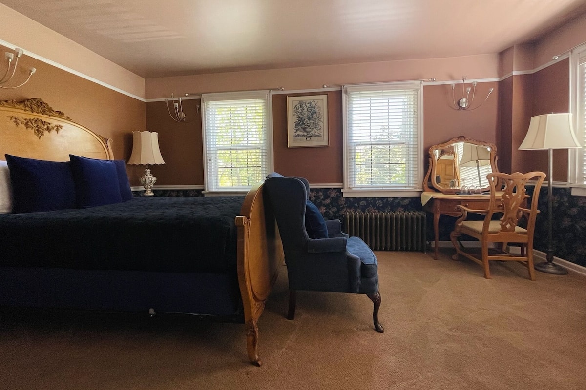 Un dormitorio con cama, una silla, un escritorio y un radiador.