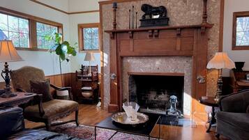 A cozy living room with a fireplace, wooden furniture, and a large window.