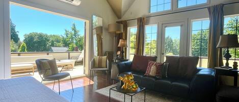 A spacious living area with a large window, a sofa, a coffee table, and a chair.