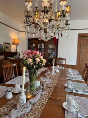 Una mesa de comedor dispuesta con una araña, un florero y una vela.