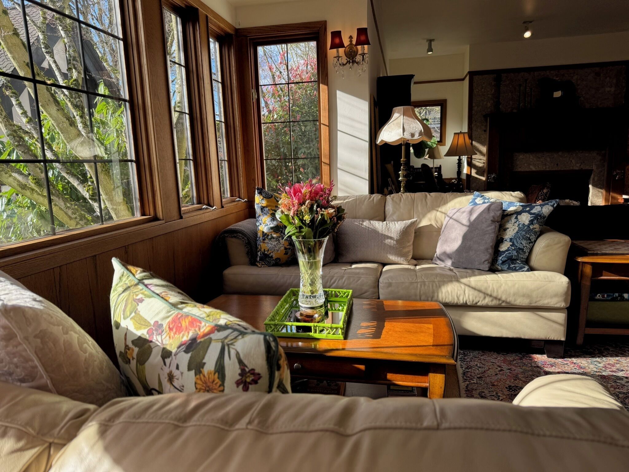 A cozy living room with a sofa, a coffee table, and a vase of flowers.