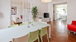 A modern living space with a dining area, a red chair, a television, and a plant. - 200m2 luxury apartment in a secure private alley. Center of Paris (PARIS)