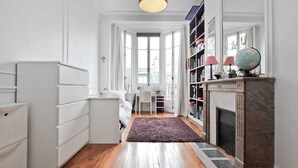A room with a bed, a desk, a bookshelf, a fireplace, and a large window. - 200m2 luxury apartment in a secure private alley. Center of Paris (PARIS)