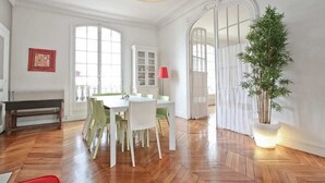 A dining area with a round table, chairs, a bench, and a potted plant. - 200m2 luxury apartment in a secure private alley. Center of Paris (PARIS)