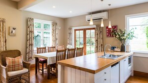 A kitchen with a wooden island, white cabinetry, and a dining area with wooden chairs. - Family-friendly, well-equipped, spacious country house,garden and Fibre Internet (Ohoka)