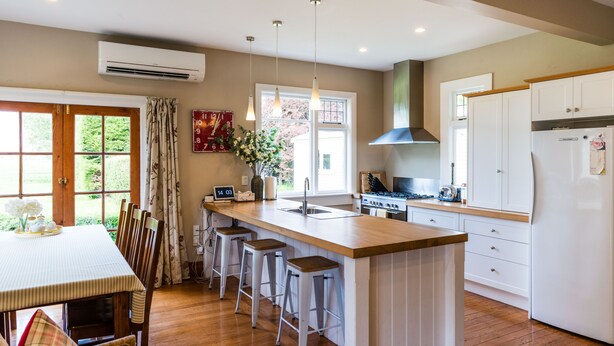 A modern kitchen with a central island, bar stools, a stove, and a refrigerator. - Family-friendly, well-equipped, spacious country house,garden and Fibre Internet (Ohoka)