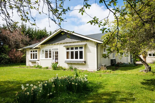 Ein eingeschossiges Haus mit Satteldach, einer Veranda und einem kleinen Garten mit Narzissen.