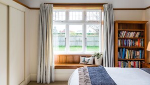 A bedroom with a large window, a wooden bookshelf, and a bench with a pillow and a plant. - Family-friendly, well-equipped, spacious country house,garden and Fibre Internet (Ohoka)
