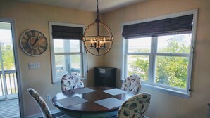 Une salle à manger avec une table ronde, quatre chaises, une horloge et un lustre.