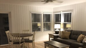 Una sala de estar con una mesa de comedor, sillas, un sofá, una mesa de centro y un sillón estampado.