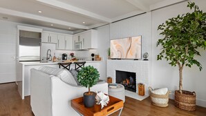 A modern living room with a fireplace, a dining area, and a kitchen.
