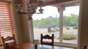 A wooden dining table with chairs, a metal pot, and a window with blinds. - Perfect Home for Super Bowl & Waste Management Open in Boulders on the N. Course (Carefree)