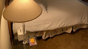 A hotel room with a large bed, a bedside table with a lamp, a chair, and a window with curtains. - Perfect Home for Super Bowl & Waste Management Open in Boulders on the N. Course (Carefree)