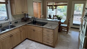 A spacious kitchen with granite countertops, wooden cabinets, and a central island. - Perfect Home for Super Bowl & Waste Management Open in Boulders on the N. Course (Carefree)