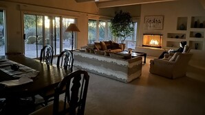 A spacious living room with a dining area, large windows, a ceiling fan, and a fireplace. - Perfect Home for Super Bowl & Waste Management Open in Boulders on the N. Course (Carefree)