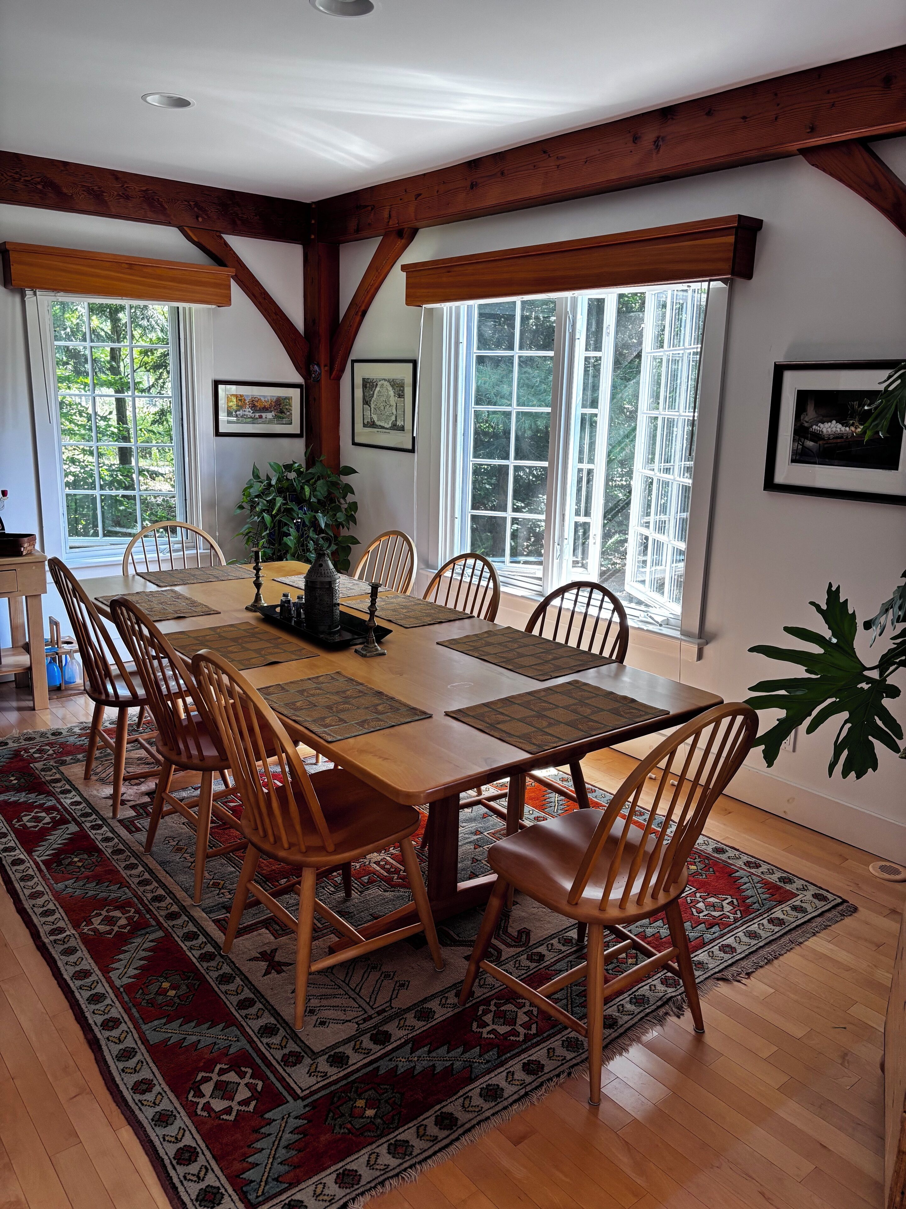 A dining area with a wooden table, chairs, and a rug.