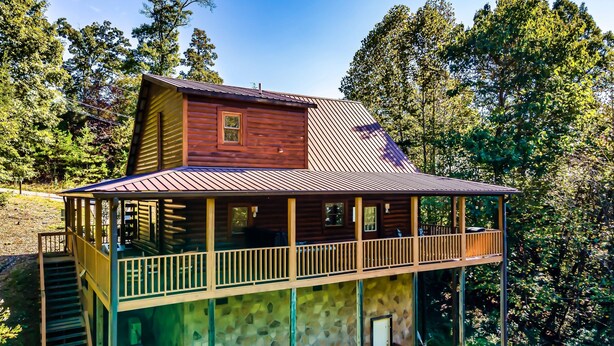 A two-story log cabin with a balcony and a stone foundation. - Awesome deals, King bed, Hot Tub, Private, Arcade, Real log cabin (Sevierville)