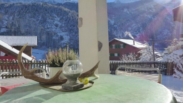 Una mesa con un centro de vidrio y asta, vista a montañas nevadas y una valla de madera.