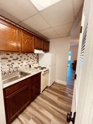 A kitchen with wooden cabinets, a white refrigerator, a stove, and a sink.