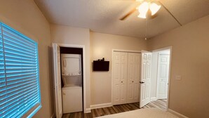Ein Schlafzimmer mit Bett, Waschmaschine, Trockner und Deckenventilator.