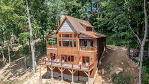 A wooden cabin with a balcony, surrounded by trees.