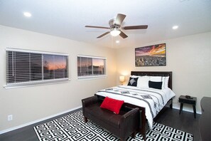 A bedroom with a bed, two windows, a ceiling fan, a painting, a bedside table, and a patterned rug. - Cozy 3BR Retreat w/Amazing Outdoor Deck Near Randolph AFB & JBSA Ft. Sam Houston (Converse)
