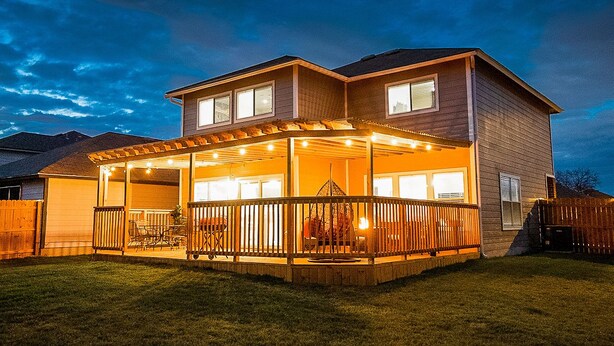 A two-story house with a covered patio area, a fenced backyard, and a garage.