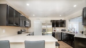 A modern kitchen with dark cabinets, a central island, and a refrigerator.