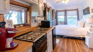 Ein kompaktes Wohnmobil-Interieur mit Küchenzeile, einem Bett und Deckenventilator.