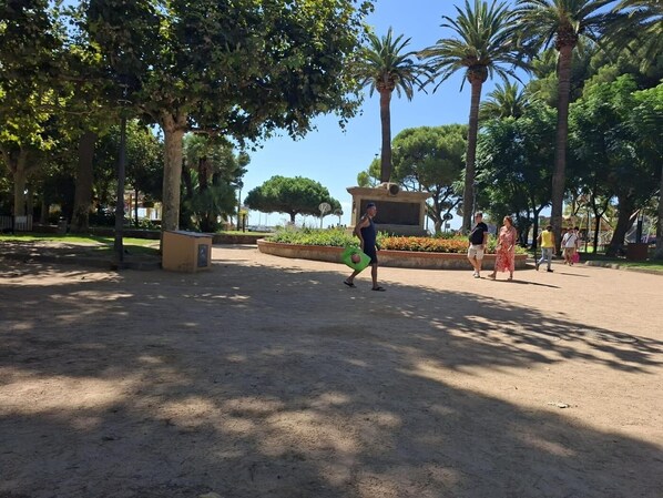 A park with trees, a fountain, and a statue.
