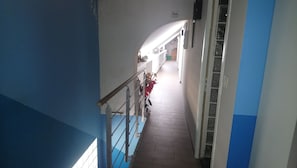 Un corridoio stretto con ringhiera in metallo, una scala e una porta che dà su un'altra stanza.