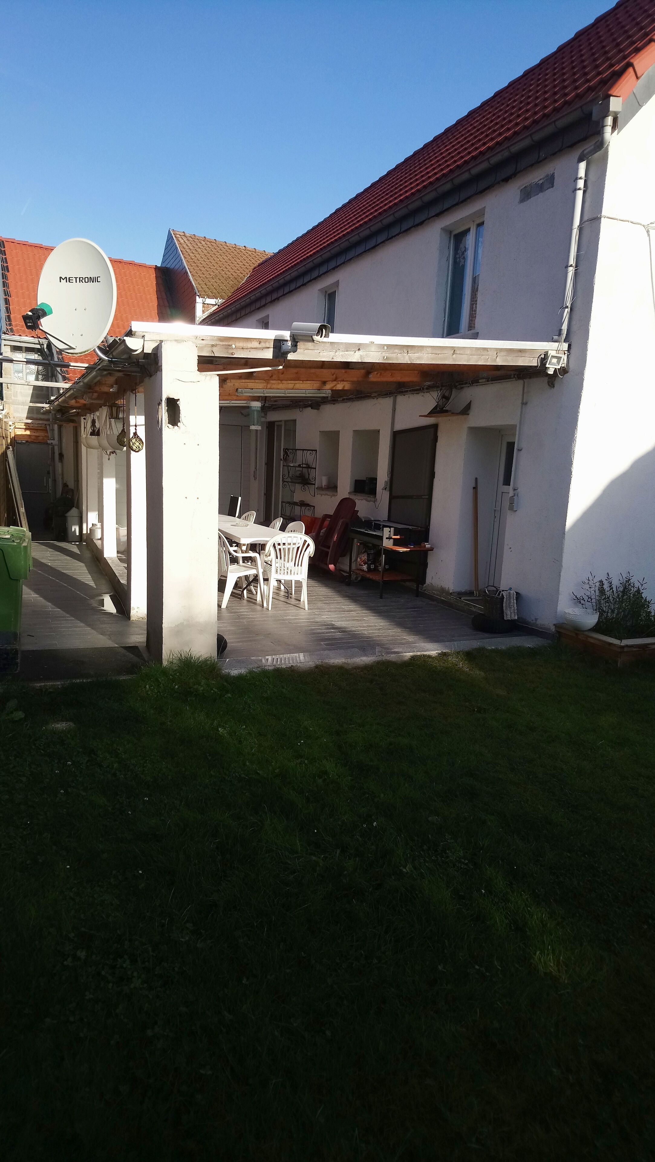 A house with a covered patio, satellite dish, and outdoor furniture.