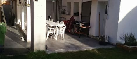 Una casa con porche cubierto, antena parabólica y mobiliario de exterior.