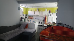Un ambiente compatto con angolo cottura, divano e un piccolo tavolo da pranzo.