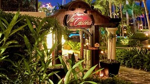 Une enseigne de restaurant sur le thème des tropiques, entourée de palmiers et bordée de chemins bien éclairés.