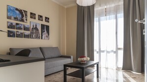 Una sala de estar moderna con un sofá gris, una mesa de centro negra y una pared decorada con fotografías de un paisaje urbano.