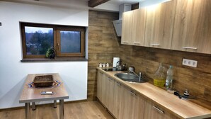 A modern kitchen with wooden cabinets, a stainless steel sink, and a window with a view of trees. - Private cottage near Tykocin (Tykocin)