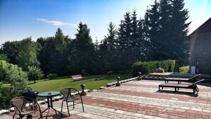 A patio with outdoor furniture, a grill, and a view of a grassy area with trees. - Private cottage near Tykocin (Tykocin)