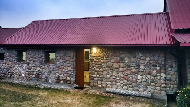 A stone building with a red roof and a wooden door. - Private cottage near Tykocin (Tykocin)