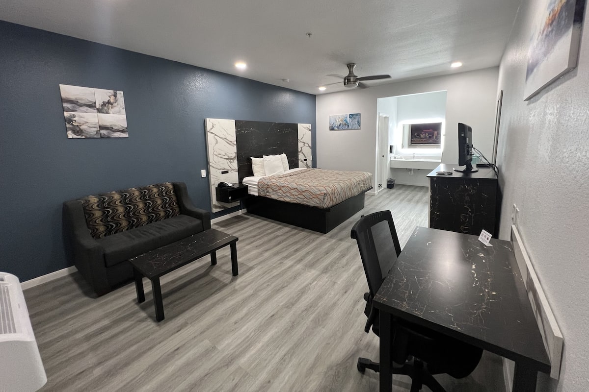A modern bedroom with a bed, a desk, and a sofa.