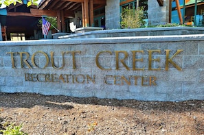 A sign for Trout Creek Recreation Center with a stone wall and an American flag. - Mountain Getaway | 3 King Beds & Clubhouse Access | 3-min walk to Trails (Truckee)